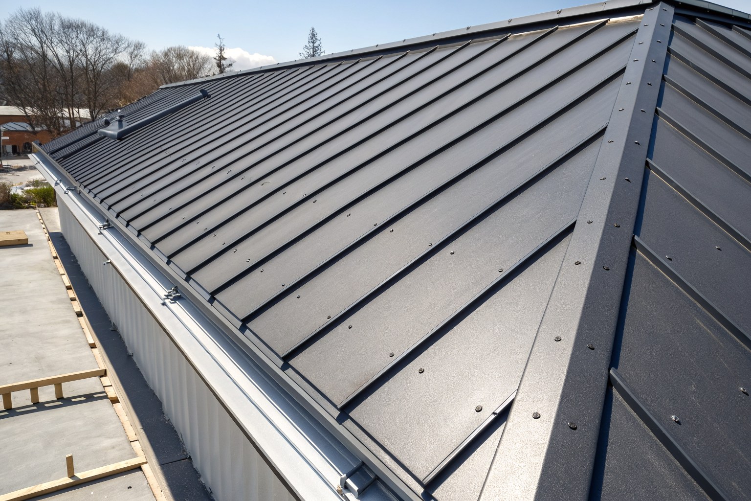 Close view of dark gray standing-seam metal panels in low sunlight