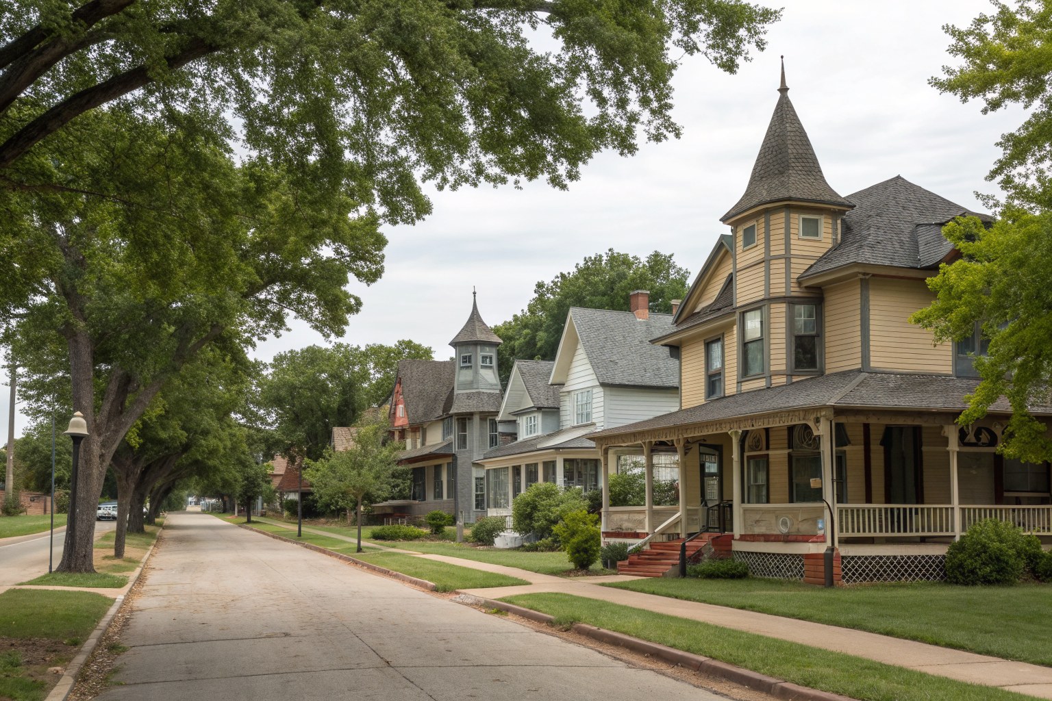 A tree-lined street of restored Victorian homes with steep shingle roofs and porches
